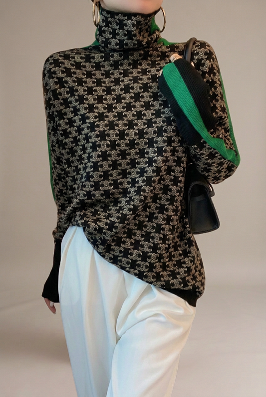Modelo con jersey de cuello alto Sibyl negro y gris con detalles verdes sobre fondo beige grisáceo limpio, sin muebles.