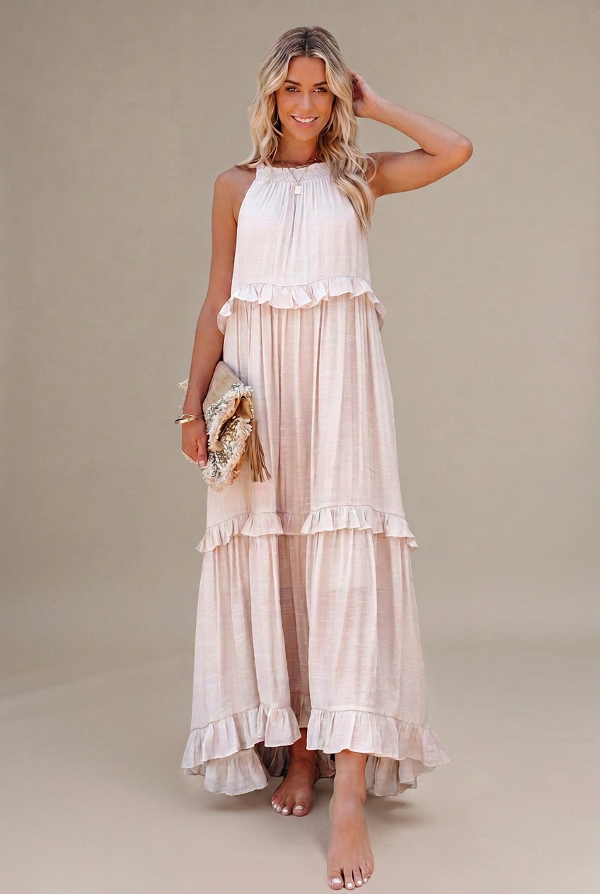 Modelo con vestido largo marfil con volantes sobre fondo beige grisáceo limpio, sin elementos decorativos.